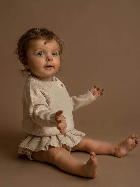 Hanevild vauvan neulebody frillahameella kermanvaalea, pehmeä luomupuuvilla ja villa